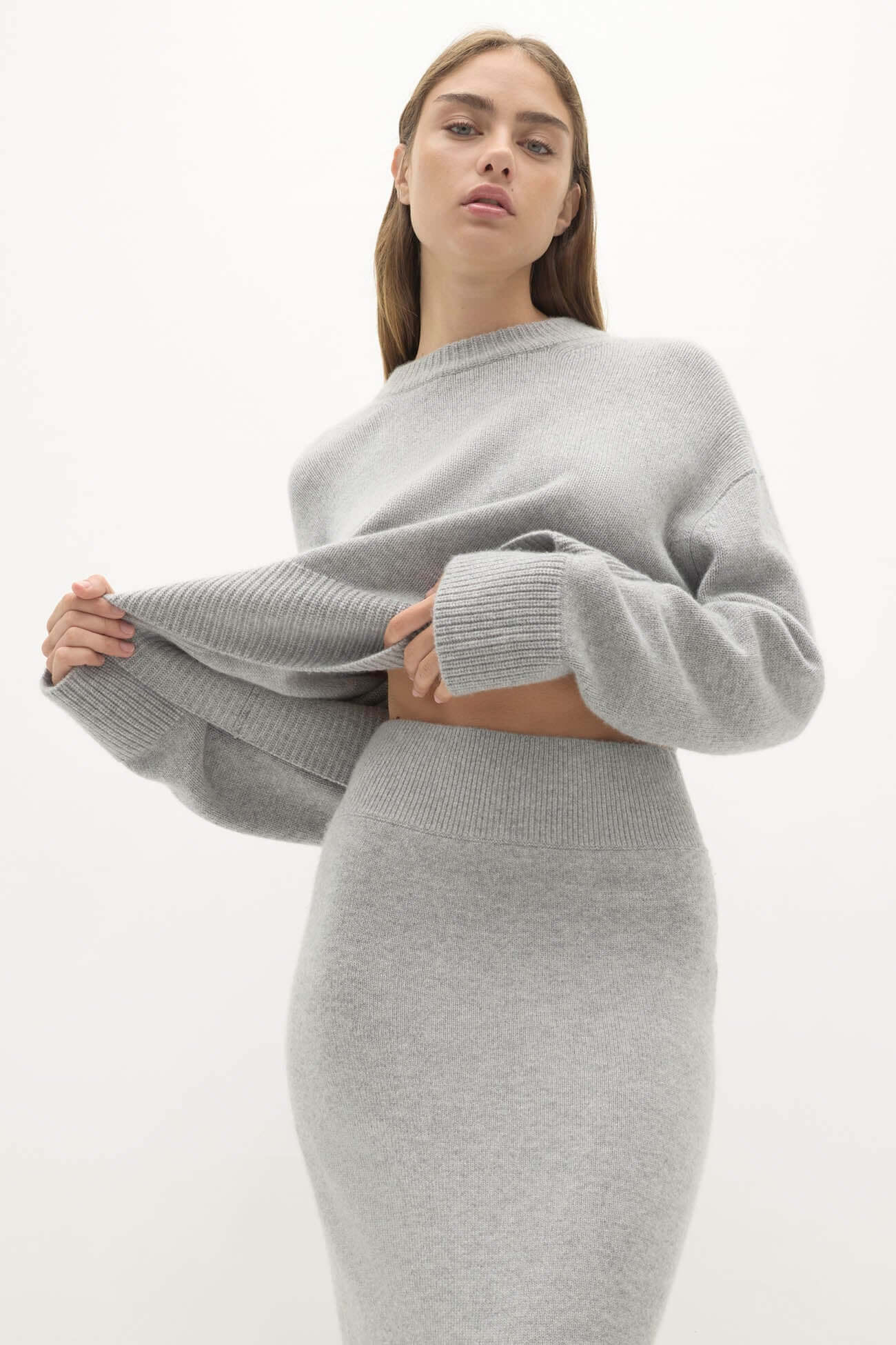Model showcasing stylish gray outfit in Sets separates collection, featuring a cozy sweater and fitted skirt.